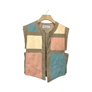 May include: A tan vest with colorful patchwork squares in pastel shades of blue, yellow, and pink. The vest is sleeveless and has a quilted design. The brand name "Pachington" is visible on the collar.