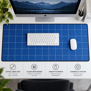 May include: A rectangular desk mat featuring a blue grid pattern with white lines. The mat measures 80 by 40 cm. A white wireless keyboard and a white computer mouse are placed on the mat, which is positioned below a computer monitor.