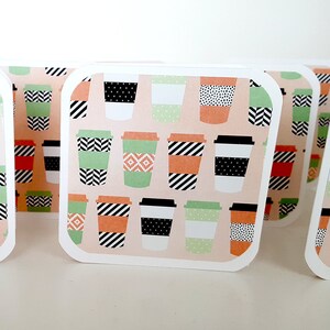 May include: A set of six blank greeting cards featuring a repeating pattern of colourful coffee cups on a peach background. The cards are white with rounded corners and a white border.