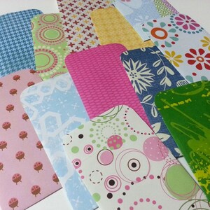 May include: A collection of colorful patterned paper envelopes with rounded corners. The envelopes feature various designs, including polka dots, flowers, geometric shapes, and abstract patterns.