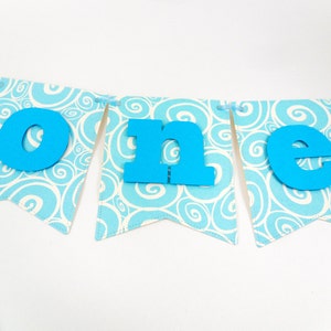 May include: A blue and white banner with the word "one" in large blue letters. The banner is decorated with a swirling pattern.