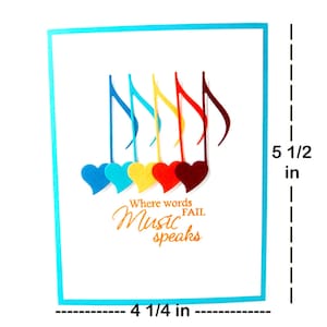 May include: A white card with a blue border, featuring a colorful design of musical notes and hearts. The text "Where words fail Music speaks" is printed in orange.