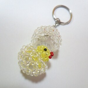 May include: A yellow beaded chick hatching from a clear beaded egg with a silver key chain attached.