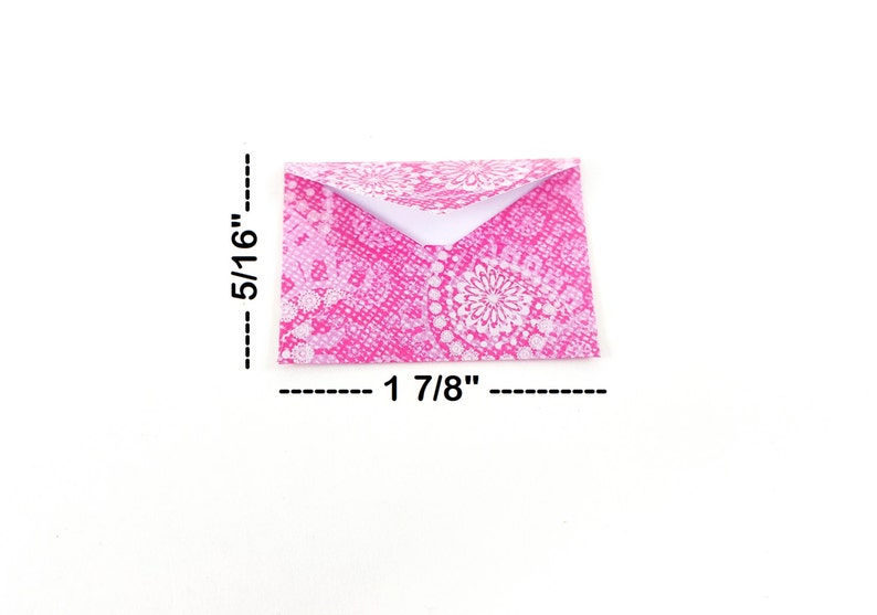 May include: A small, folded envelope with a pink floral pattern. The envelope measures 1 7/8 inches wide and 5/16 inches high. The design features a white floral pattern on a pink background.