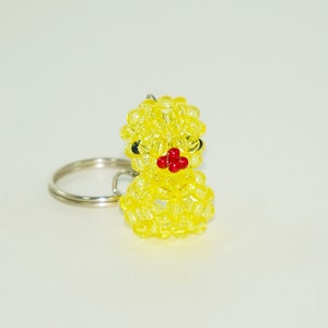 May include: A yellow beaded keychain shaped like a chick with black eyes and a red beak.
