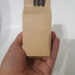 Puede incluir: Una bolsa de papel marr&oacute;n con una grapa negra en la parte superior.