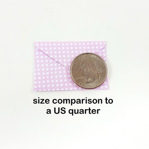 May include: A small, light purple envelope with white polka dots is shown next to a US quarter for size comparison. The text "size comparison to a US quarter" is below the objects.