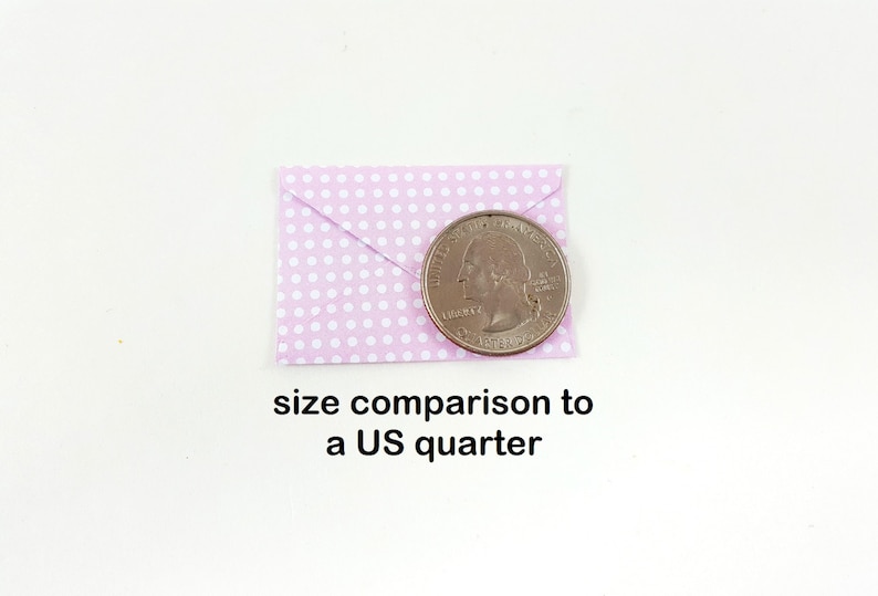 May include: A small, light purple envelope with white polka dots is shown next to a US quarter for size comparison. The text "size comparison to a US quarter" is below the objects.