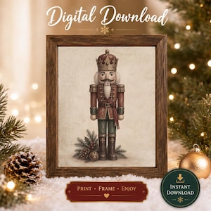 Op de afbeelding: Een digitale download-print met een notenkraker-illustratie in een donkerhouten lijst. De notenkraker draagt een kroon, een rood jasje en een donkere broek, staand naast dennentakken, hulst en een bel. Tekst leest Digital Download.