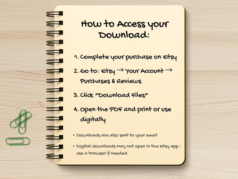 May include: A spiral-bound notebook with instructions on how to access a digital download from Etsy. The text is in black ink on a cream-colored page. Green paper clips are in the lower left corner. The notebook is on a light wood surface.