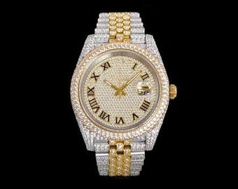 Pode incluir: Um relógio de luxo com pulseira em ouro e prata e mostrador cravejado de diamantes. O relógio apresenta algarismos romanos e um visor de data. O relógio está sobre um fundo preto.