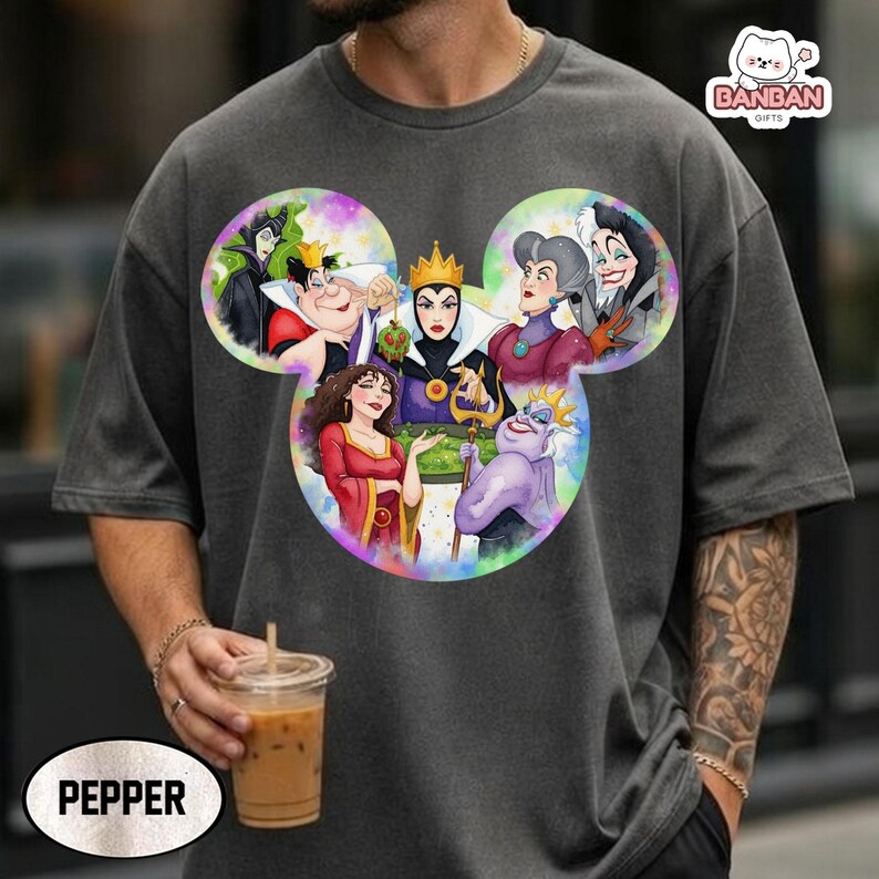 A person wearing a gray t-shirt with a colorful graphic of Disney characters, including a group of women and a character with a crown. The person is holding a drink in their hand.
