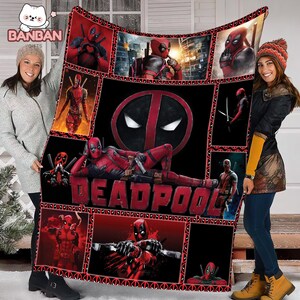two women standing next to each other, holding a quilt or blanket with the word "Deadpool" printed on it. The quilt is decorated with various images of the Marvel superhero Deadpool, including his iconic red and black costume, his signature mask, and other recognizable poses and expressions.