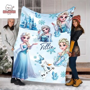 two women holding up a large blanket with illustrations of characters from the Disney movie Frozen.