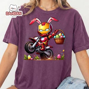 A purple t-shirt with a cartoon image of a bunny character wearing a helmet and holding a basket of Easter eggs.