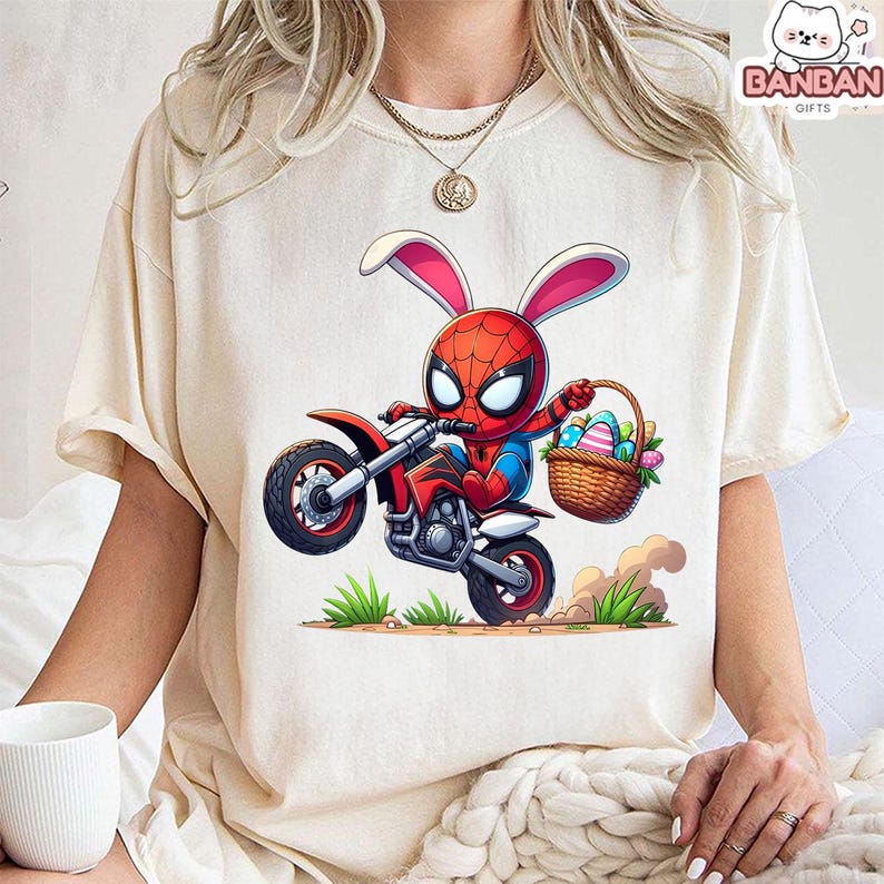 A person wearing a white t-shirt with a graphic of Spider-Man riding a motorcycle and holding a basket of Easter eggs.