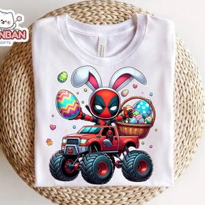 A white t-shirt with a graphic design depicting a character in a red and black costume riding a monster truck, holding a basket of Easter eggs.