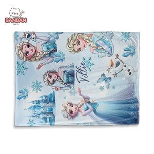 A blanket featuring various characters from the Disney movie Frozen, including Elsa, Olaf, and other popular characters. The blanket has a snowy, winter theme with snowflakes and a castle in the background.