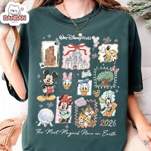 A green t-shirt with various Disney characters and landmarks printed on it, along with the text "Disney World" and "2026".