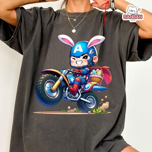 A person wearing a black t-shirt with a graphic of a cartoon character riding a motorcycle.