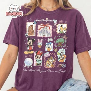 A purple t-shirt with a collage of Disney characters and iconic landmarks, including Mickey Mouse, Minnie Mouse, Donald Duck, Goofy, and the Eiffel Tower. The text on the t-shirt reads "The Most Magical Place on Earth" and "Disney World 2026".