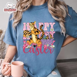 A person wearing a blue t-shirt with a cartoon image of Tigger, a character from Winnie the Pooh, and the text "Happy Easter" printed on it.