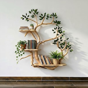 Op de afbeelding: Een uniek, boomvormig wandrek gemaakt van natuurlijk hout. Het ontwerp heeft meerdere planken voor boeken en decoratieve items, met kunstmatige groene bladeren. De planken bevatten boeken en potplanten.