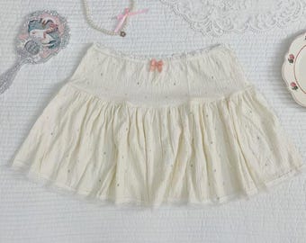 Cremefarbener Minirock aus knitterfreier Baumwolle, gestuft mit gepunktetem Spitzenbesatz, verspielter, koketter Stil