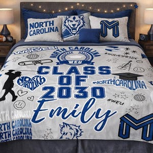 May include: A bedroom scene featuring a bed with a custom blanket and pillows. The blanket is light gray with blue text that reads "Class of 2030 Emily" and "North Carolina". Decorative pillows and wall art complement the theme.