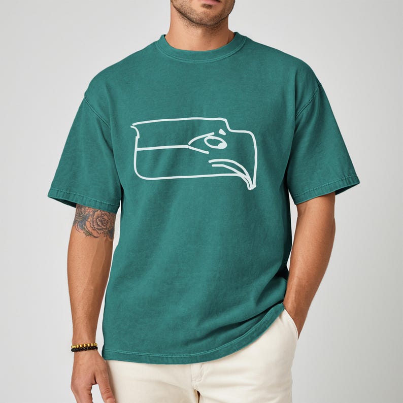 Seattle football team meme shirt designed as a Sam Darnold hand drawn logo shirt with humorous illustrated details, funny Seattle sports t shirt perfect for championship winner celebrations, ideal gift for football fan shirt, unisex football apparel great for game days, tailgating events, watch parties, casual wear, sports bar outfits, Seattle themed fan clothing, and meme lovers who enjoy playful sports fashion