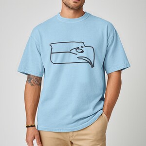 Funny Seattle sports t shirt showing a Sam Darnold hand drawn logo shirt design inspired by Seattle football team meme culture, championship winner t shirt created for fans who love humor and bold graphics, ideal gift for football fan shirt, unisex fit perfect for game day outfits, tailgates, watch parties, sports bars, casual everyday wear, and Seattle football supporters who enjoy meme inspired apparel