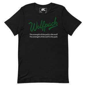 Puede incluir: Camiseta negra con la palabra "Wolfpack" en verde. Debajo, el texto dice: "La fuerza de la manada es el lobo. La fuerza del lobo es la manada" en blanco.