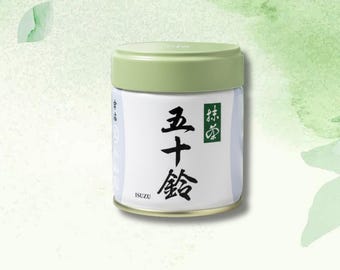 May include: A cylindrical container of matcha tea with a light green lid and a white label. The label features Japanese characters in black and a green square with more Japanese text. The brand name "ISUZU" is printed at the bottom.