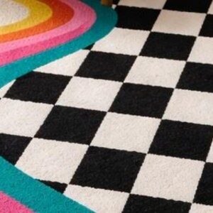 Artistic hand-tufted area rug featuring colorful organic wave stripes sweeping across one side into a timeless checkerboard pattern in black and ivory. Made from premium wool by skilled artisans, this contemporary rug offers plush comfort, bold geometric style, and a playful retro aesthetic that enhances living rooms, bedrooms, offices, lofts, and creative home décor.