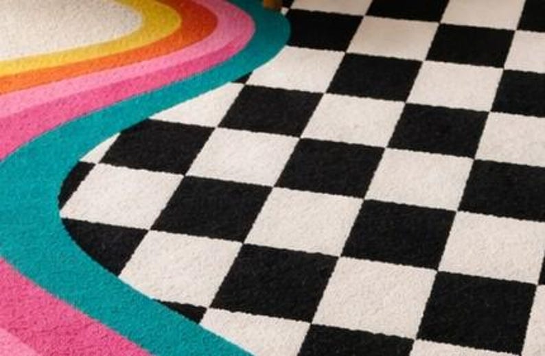 Artistic hand-tufted area rug featuring colorful organic wave stripes sweeping across one side into a timeless checkerboard pattern in black and ivory. Made from premium wool by skilled artisans, this contemporary rug offers plush comfort, bold geometric style, and a playful retro aesthetic that enhances living rooms, bedrooms, offices, lofts, and creative home décor.
