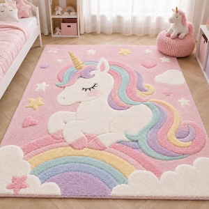 May include: A pink rectangular rug featuring a white unicorn with a golden horn, rainbow mane, and a rainbow. The rug has star, heart, and cloud accents. This whimsical rug is perfect for a child's bedroom.