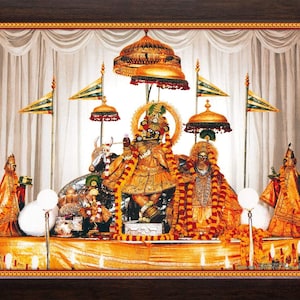 May include: A framed religious artwork depicting a golden deity with elaborate ornamentation, surrounded by flags and decorative elements. The artwork features a detailed display with a warm color palette, including gold, orange, and white.