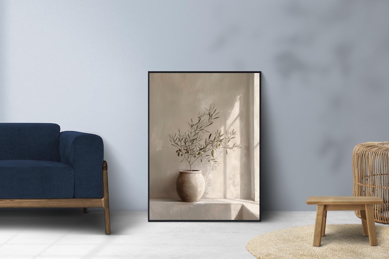 Op de afbeelding: Een ingelijste kunstdruk met een beige vaas met olijftakken. De vaas staat op een richel tegen een neutrale muur, met zonlicht dat door een raam schijnt. Het kunstwerk is in een zwart frame.