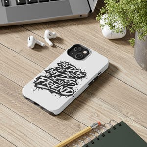 Puede incluir: Funda de teléfono blanca con un diseño gráfico en blanco y negro que dice "MY DOG IS NOT MY DOG IS MY FRIEND". La funda está sobre una superficie de madera, junto con un portátil, auriculares, un lápiz y un cuaderno.