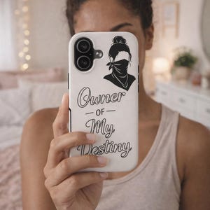 Puede incluir: Funda de teléfono blanca con un gráfico negro de una mujer con pañuelo y moño. El texto "Owner of My Destiny" está escrito en una fuente elegante. La funda tiene un borde negro y dos lentes de cámara.