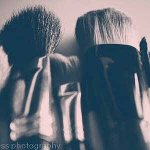 May include: Close-up of several makeup brushes with black handles and soft bristles. The image has a sepia tone, with the brushes arranged closely together. The text "jessica reiss photography" is visible at the bottom.