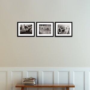 May include: Three black framed photographs on a white wall. The photos are in black and white and show a pile of wine corks, two wine glasses, and a corkscrew.