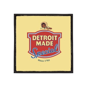 Könnte beinhalten: Quadratischer Aufnäher mit schwarzem Rand und hellgelbem Hintergrund. Der Aufnäher zeigt ein rot-blaues Schilddesign mit den Worten "DETROIT MADE Special" und eine kleine Illustration einer Person. Der Text "Since 1701" befindet sich unten.
