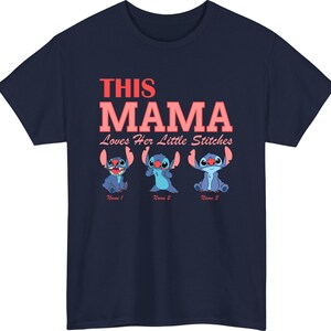 May include: Navy blue t-shirt featuring the text "THIS MAMA Loves Her Little Stitches" in red and pink. Below the text are three cartoon Stitch characters in different poses. The shirt is a crew neck.