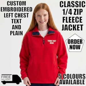 May include: A red fleece jacket with a quarter-zip and a navy collar. The jacket features a front pocket and the text "YOUR TEXT HERE" embroidered on the chest. The image also includes the text "CUSTOM EMBROIDERED LEFT CHEST TEXT AND PLAIN".
