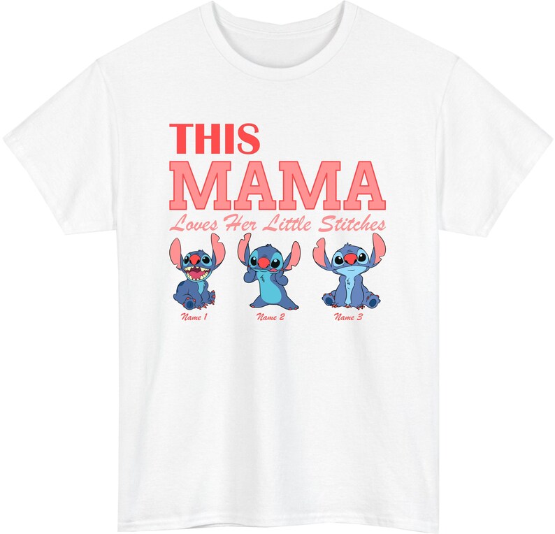 May include: White t-shirt featuring the text "THIS MAMA Loves Her Little Stitches" in red and pink. Below the text are three blue cartoon characters. The shirt is a crew neck style.