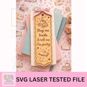 Könnte beinhalten: Ein hölzerner Lesezeichen mit dem Text "Buy me books & tell me I'm pretty" wird angezeigt. Das Lesezeichen hat ein Kaffeebecher- und Buchdesign. Es ist mit einem rosa Band gebunden und liegt auf einem Stapel Bücher.