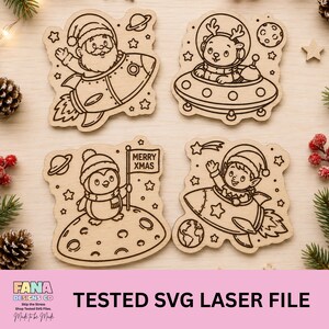 May include: Four laser-cut wooden ornaments featuring engraved space-themed holiday designs. One shows Santa in a rocket, another a reindeer in a UFO, a penguin on a moon holding a flag that reads MERRY XMAS, and an elf in a rocket ship.
