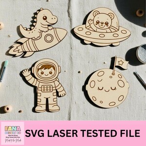 Könnte beinhalten: Vier Holz-Ausstecher mit Weltraum-Motiven. Enthält einen Dinosaurier auf einer Rakete, einen Bären in einem UFO, einen Astronauten und einen lächelnden Mond mit einer Flagge. Der Text "SVG LASER TESTED FILE" ist darunter abgebildet.