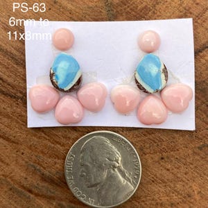 Könnte beinhalten: Zwei Sets aus Cabochons auf weißem Papier, jeweils bestehend aus einem runden hellrosa Stein, einem tropfenförmigen blau-weißen Stein mit braunen Rändern und drei kleinen hellrosa herzförmigen Steinen. Der Text lautet PS-63 6mm to 11x8mm.